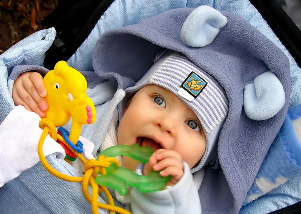 A Baby Lying and Teething a Green Toy